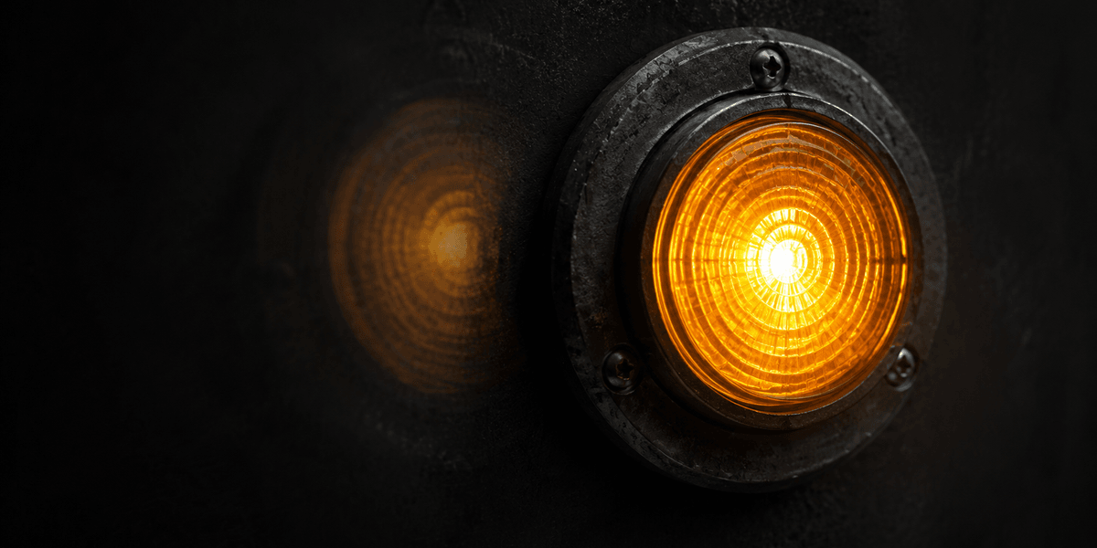 A single sharply lit circular lamp in the foreground with a softer, blurred duplicate glowing behind it, representing a clear current signal standing out against a faded, out-of-focus one