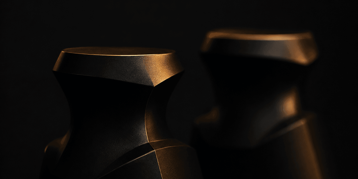 Two similar sculpted forms under the same warm light, one sharply in focus and the other blurred behind it, representing what sets an authentic website apart from an imitation