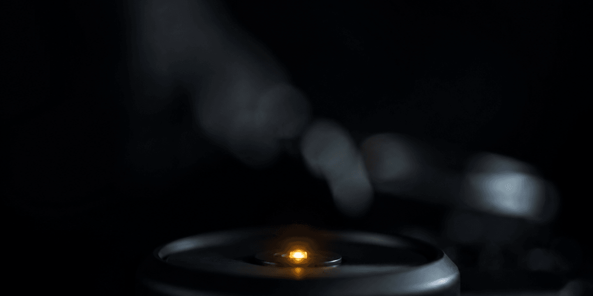 A single small point of warm light glowing at the center of a dark surface while everything around it falls out of focus — echoing how one clear, specific statement can anchor a page that would otherwise blur together