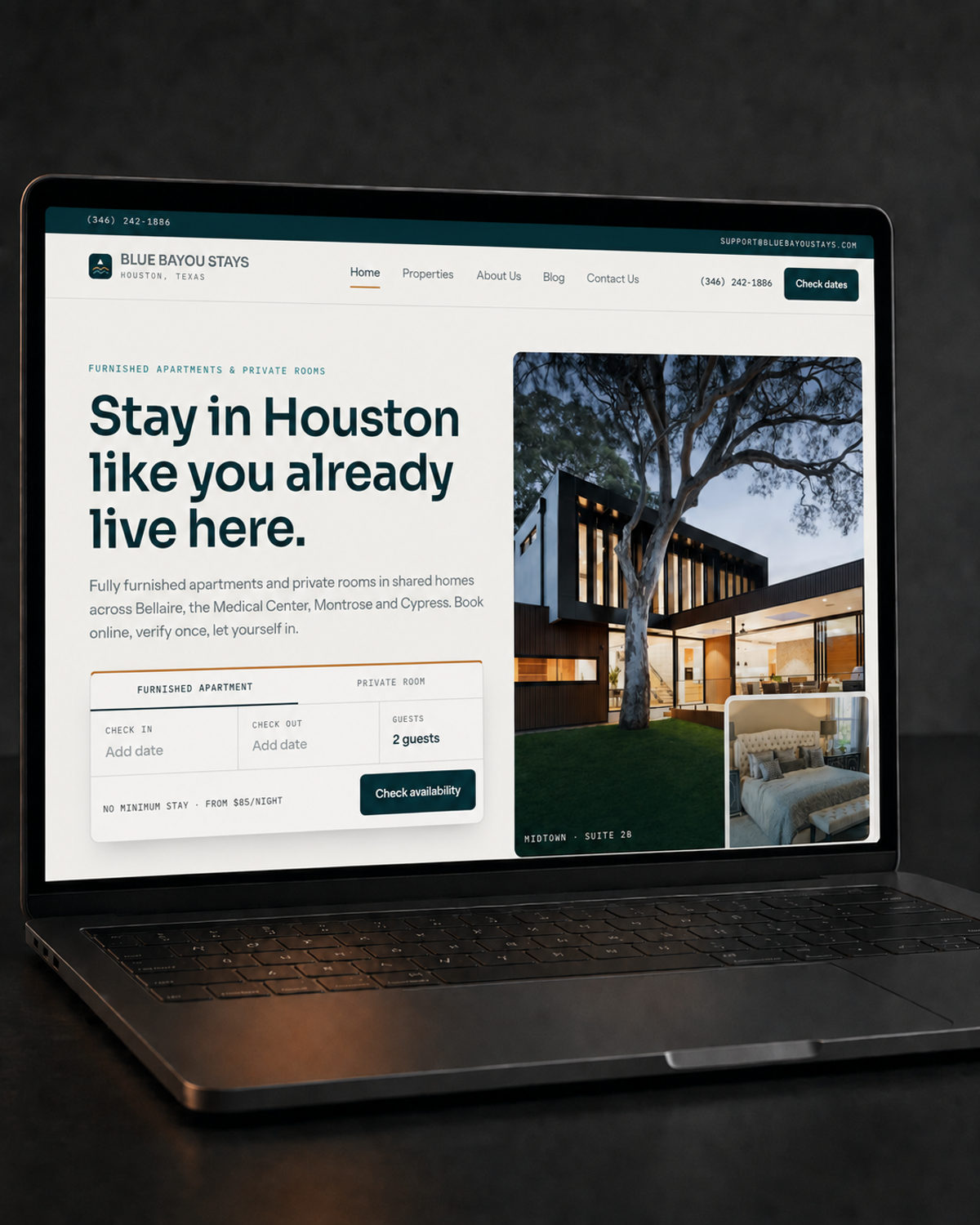 Laptop on a dark desk under a warm amber light, screen showing the Blue Bayou Stays homepage with a furnished home exterior at dusk