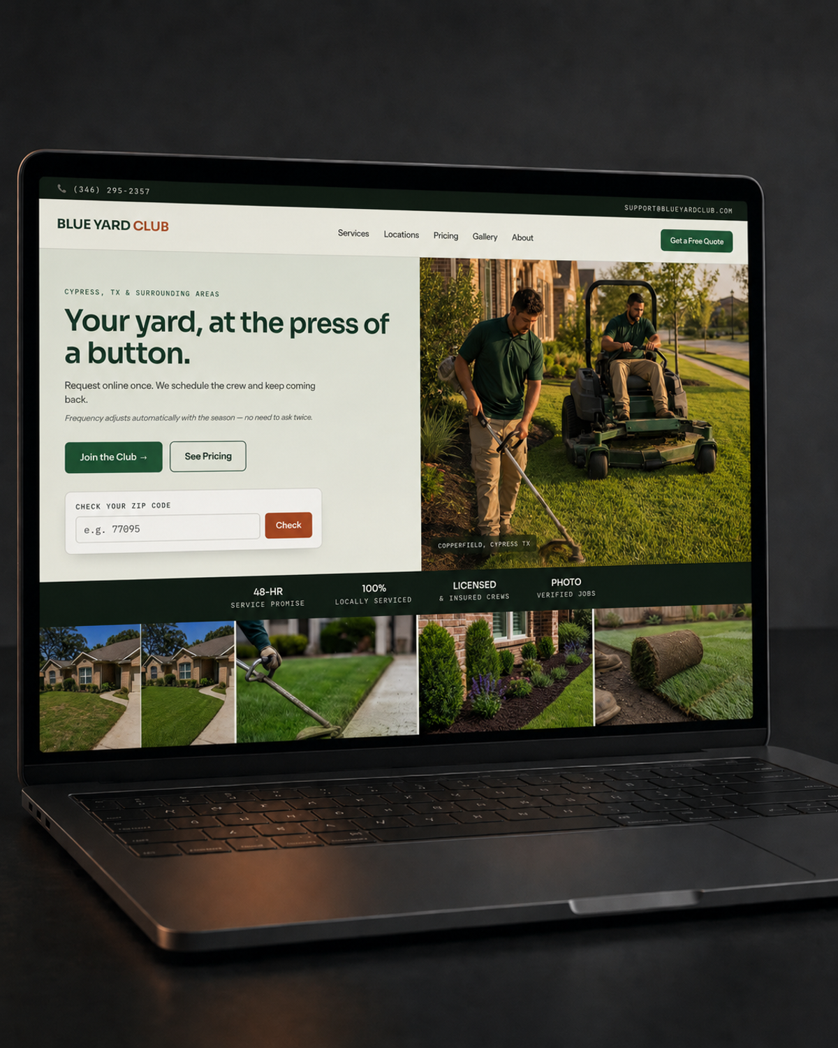 Laptop on a dark desk under a warm amber light, screen showing the Blue Yard Club homepage with a crew mowing and trimming a lawn