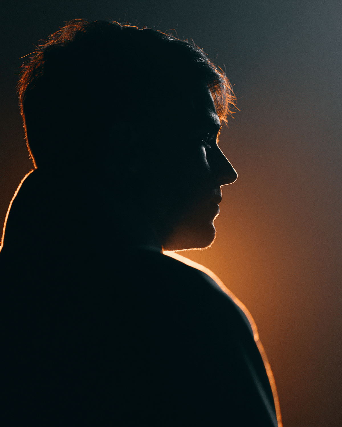 Human silhouette in side profile with warm rim light, representing individual attention rising above generic automation