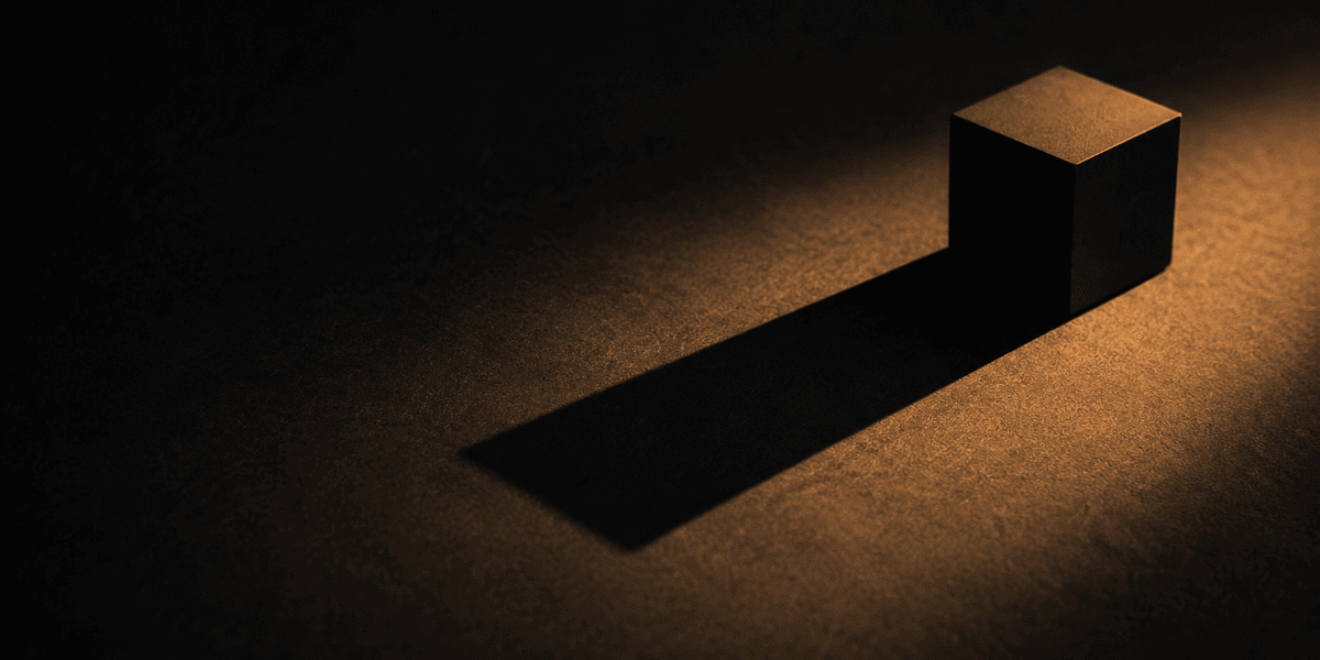 A solid cube casting a long, sharply defined shadow under warm light, representing a specific commitment with real weight that can be verified